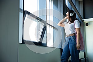 Young woman waiting for departure in airport, traveler with small baggage, influencer`s lifestyle