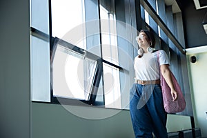 Young woman waiting for departure in airport, traveler with small baggage, influencer`s lifestyle