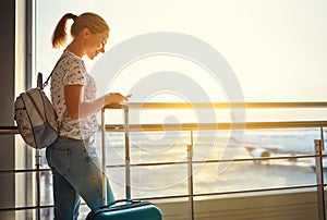 young woman waiting for flying at airport at window with suitcase .