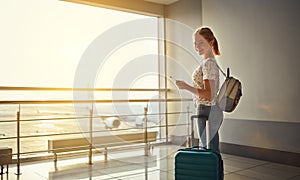 young woman waiting for flying at airport at window with suitcase .