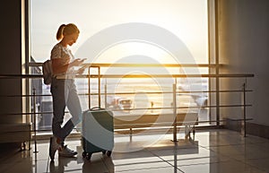 young woman waiting for flying at airport at window with suitcase .