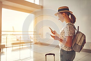 young woman waiting for flying at airport at window with suitcase