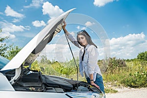 Young woman waiting for help near damaged car.