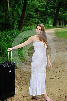 young woman waiting by road with suitcase