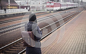 Young woman waiting train on the platform of railway station