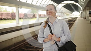 young woman waiting for a train at the station. Joy, excitement, expectation. The girl meets the train, rejoices, smiles