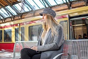 Young woman waiting for train to arrive on the platform at railway station