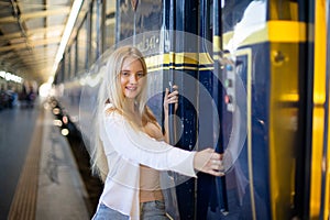 Young woman waiting in vintage train, relaxed and carefree at the station