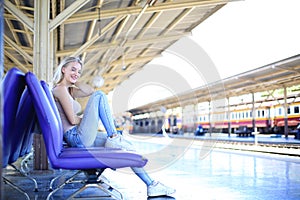 Young woman waiting in vintage train, relaxed and carefree at the station platform in Bangkok, Thailand before catching a train.