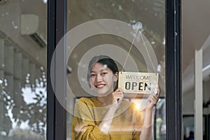 Young woman is a waitress in an apron, the owner of the cafe stands at the door with a sign Open waiting for customers