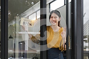 Young woman is a waitress in an apron, the owner of the cafe stands at the door with a sign Open waiting for customers