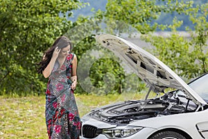 Young woman waits for assistance near her car broken down on the