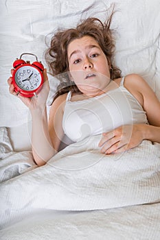 Young woman is waking up. She oversleep and is shocked photo