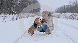 Young woman for a walk with a beagle dog in a winter park