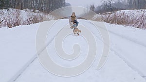 Young woman for a walk with a beagle dog in a winter park