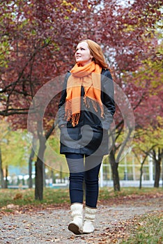 Young woman walk on footpath in autumn park, yellow leaves and trees
