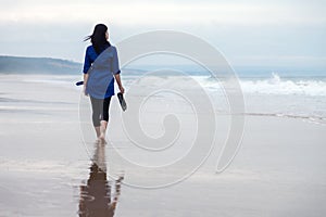 Young woman walking alone on a beach