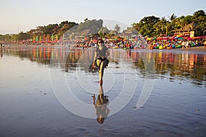 Young woman walking alone on beach at sunset with bare foot. Seminyak Beach, Bali, Indonesia