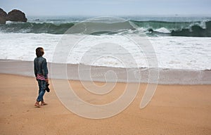 Young woman walking alone on the deserted coast of the Atlantic