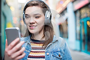 Mladá žena podél ulice streamování hudba mobilní telefon 