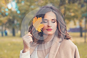 Young woman walking in autumn park and dreaming outdoors