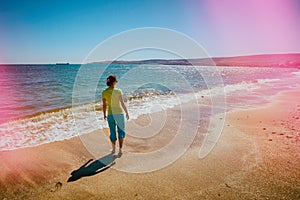 Young woman walking barefoot on the beach