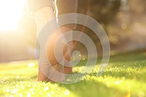 Young woman walking barefoot on fresh green grass, closeup