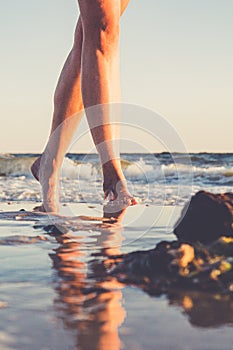 Young woman walking barefoot on sand beach. Close up view to female feet