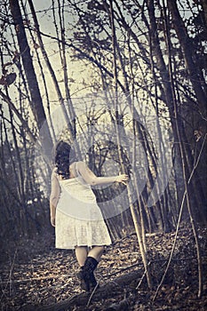 Young woman walking in barren forest