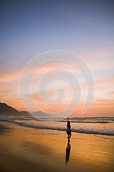 Young woman walking at the beach at sunrise in Ubatuba, Sao Paulo, Brazil