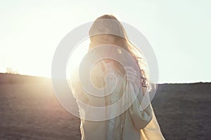 Young woman walking on beach under sunset light,