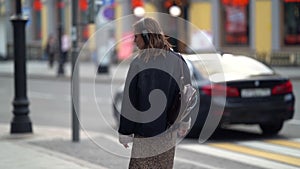 Young woman is walking in big city at fall day, using headphones for listening to music