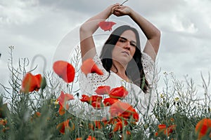 Young woman walking in a blooming poppy field