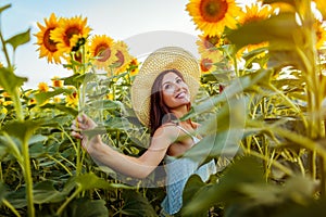 Young woman walking in blooming sunflower field feeling free and admiring nature. Summer vacation