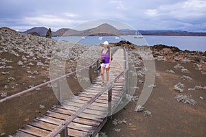 Young woman walking on a boardwalk on Bartolome island, Galapagos National Park, Ecuador.