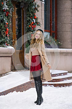 A young woman walking through the city`s snow-covered streets holds a potted Christmas tree in her handsg. Christmas holidays