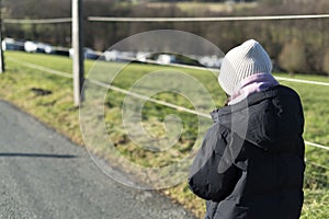 Young woman walking on a country road in winter. Rear view