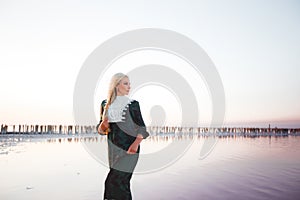 Young woman walking on Dead Sea with beautiful sky at pink sunrise