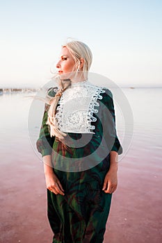 Young woman walking on Dead Sea with beautiful sky at pink sunrise