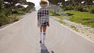 young woman walking down a road at sunset