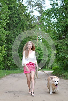 Young woman walking with golden retriever