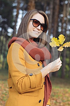 Young woman walking holding autumn leaves in park