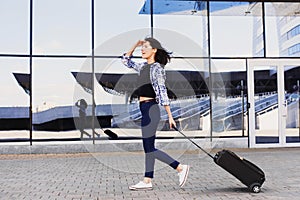 Young woman walking with luggage suitcase, vacations, travel and active lifestyle concept