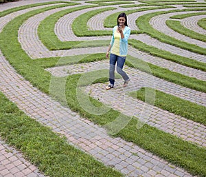 Young Woman Walking Through Maze with Cellphone
