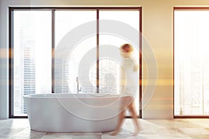 Woman walking in bathroom with tub