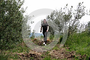 Young woman walking in nature between olive trees