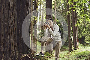 Young woman walking in nature and taking pictures