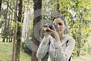 Young woman walking in nature and taking pictures