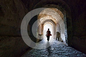 Young woman walking out of ancient tunnel