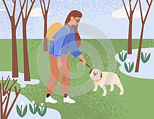 Young woman walking and playing with dog in park on a sunny spring day. Pet owner spending leisure time with puppy in